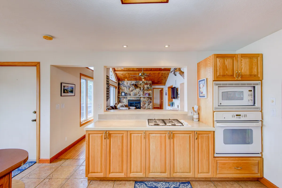 A warm, inviting kitchen space featuring a central island, stainless steel appliances, wooden cabinets, and an open layout. The scene suggests space for both cooking and gathering, with ample countertops and modern amenities that support meal preparation and family interaction.